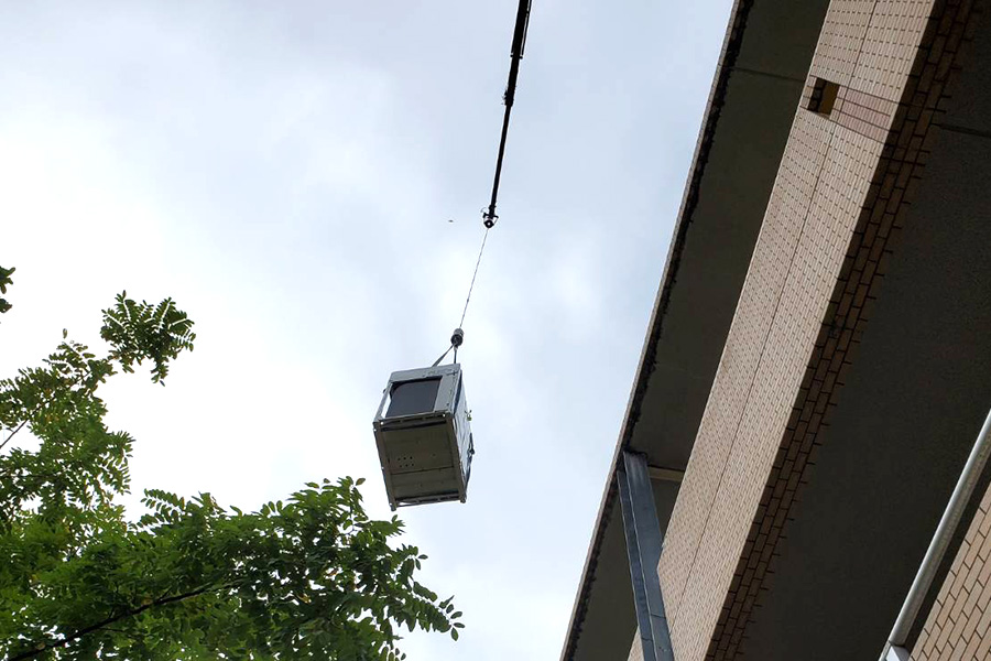 画像：クレーン車で屋上に室外機を搬入